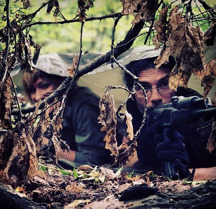 Armed man and woman in hidden bushcraft shelter