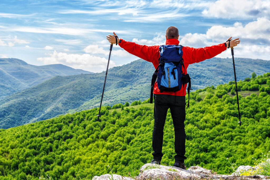 man in the mountain holding two hiking sticks